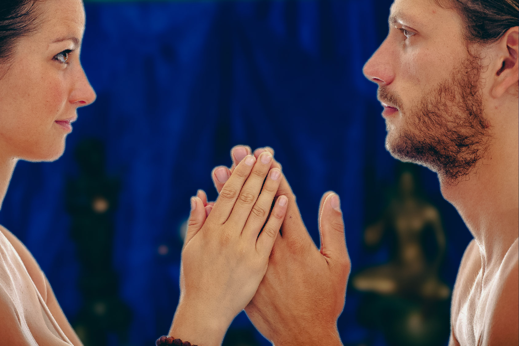 Zwei junge Menschen schauen sich in die Augen und die Hände berühren sich im Namasté
